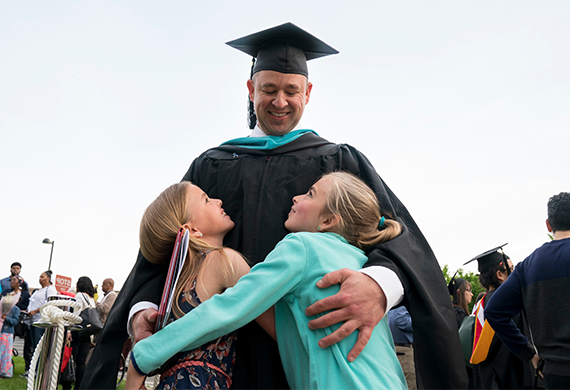 An image of an adult graduate hugging two children.